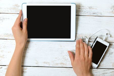 Tablet and phone with a blank screen in the hands of the girl. Top view.