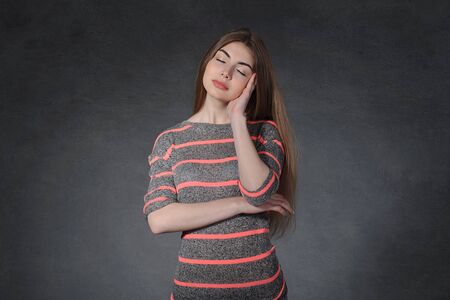 Calm, sleep, dream concept. Woman rests her head on a hand against the dark backgroundの写真素材