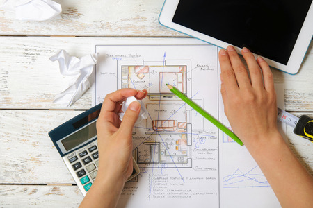 Girl draws a plan of Feng Shui for the home using the calculator and tablet. Top viewの写真素材