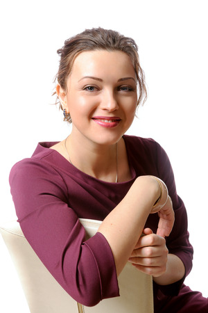 Girl in formal clothes smiling with his arms crossed while sitting on a chairの写真素材