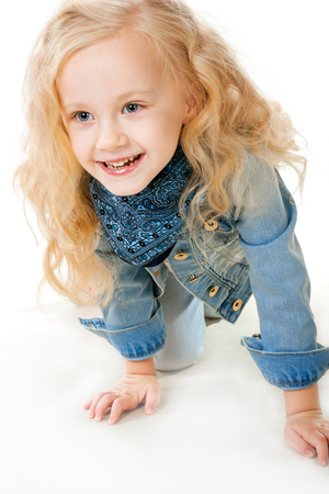 Five-year girl in a denim suit crawls on her knees forward and laughingの写真素材