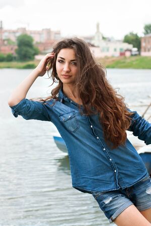 Young woman leaned to the river on the over city backgroundの写真素材