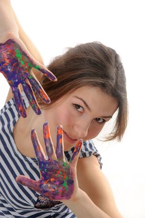 Girl looks out of her hands in the paint against an isolated backgroundの写真素材