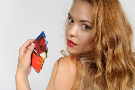 Woman holding a plastic card and thoughtfully looking up against a light backgroundの写真素材