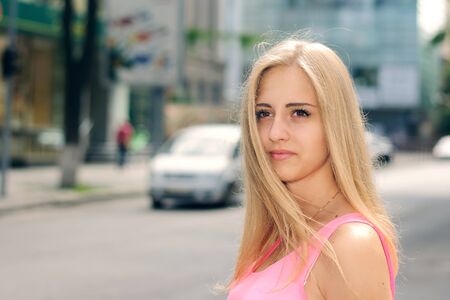 Blonde girl goes through the city against a light backgroundの写真素材