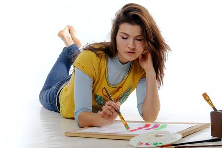 Artist intently draws lines on the paper lying on the floor facing the camera against an isolated backgroundの写真素材