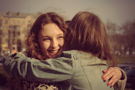 Photo in vintage style. The two girls met on the street and laugh at the background of the cityの写真素材