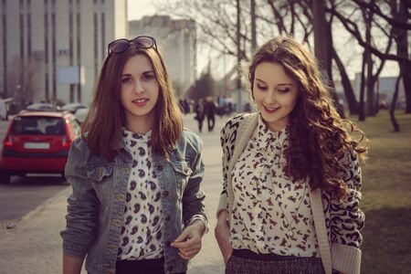 Photo in vintage style. Two girls walking on the street on a background of the cityの写真素材