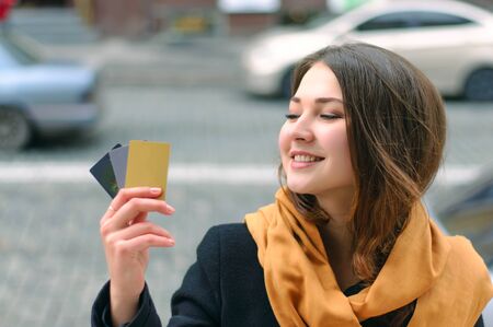Girl stands on a city street with a credit card in her hand and smilingの写真素材