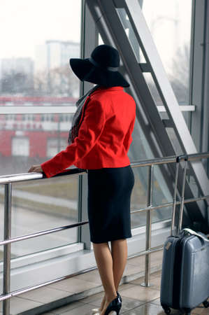 Girl in a hat and with suitcase waiting for departure in the waiting roomの写真素材