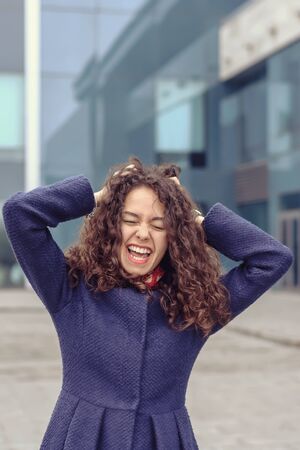 Girl screams in despair clasping hands against head office buildings