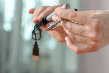 Female hand detaches part of the electronic cigarette: the battery and charging clearomizers and...