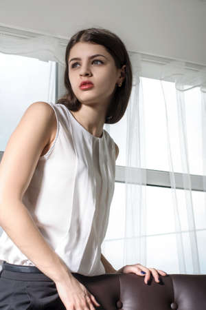 Girl posing in office. She wears smart clothes: black trousers and a white shirt. Concept: job,...