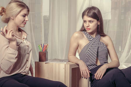 Two girls talking in an informal atmosphere the office after work. Concept: work, relaxation, timeoutの写真素材