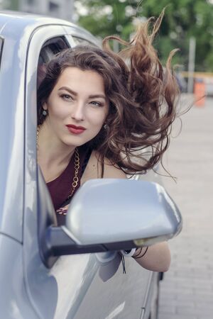 Woman looks out the car window and her hair fluttering in the wind. Concept: business, lifestyle, freedomの写真素材