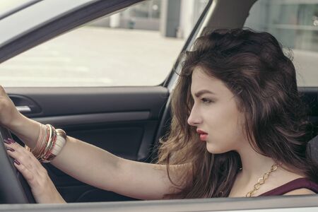 Woman is driving a car. Her gaze is focused while she turns the steering wheel. Concept:...