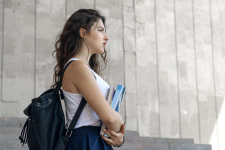 Girl goes with books in her hands. Concept: study, education, knowledge