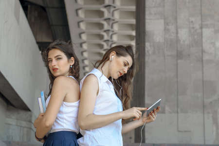 Two students are discussing about studying. They have in their hands a book and tablet. Concept: study, education, knowledgeの写真素材