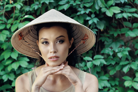 Portrait of a girl in a straw hat in the form of a cone, which is worn by women of Asian countriesの写真素材