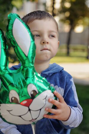 Little boy holding an inflatable rabbit outdoorsの写真素材