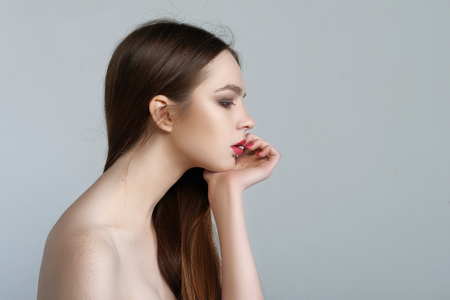 Beauty portrait of a girl with a long neck who sits sideways resting her head on her arm.の写真素材