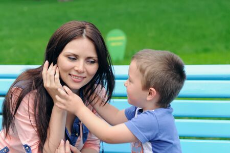 Boy pulls his hands to her mother trying to hug her. Mom closed her eyes from his gentle touchの写真素材