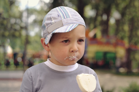Little boy eating ice cream in the park. His face was smeared with ice cream around the mouth.の写真素材