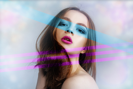 Stylized close-up portrait of a woman lined with turquoise and raspberry lines. The concept of colors in makeup.の写真素材