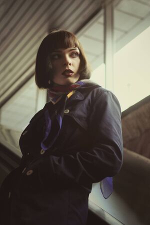 Old style vintage photo the girl on the subway stairs. She has brown hair and a bob hairstyle, she...