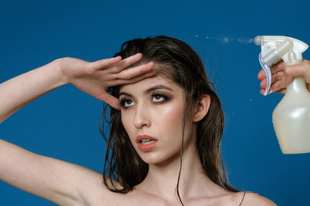 Portrait of a girl whose hair is peeing from a spray gun against a blue background in the studioの写真素材