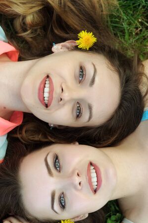 Portrait of a top view of two sisters who lie on the grass and smileの写真素材