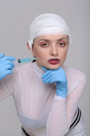 Fashion portrait of a girl with a bandage on her head who pricks drugs for skin beautyの写真素材