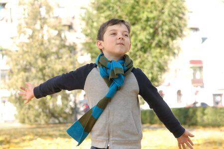 Boy running across the yard from the joyful feeling of freedom. A long scarf is tied around the boy's neckの写真素材