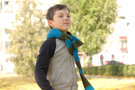 Boy walking in the park on a joyful sense of freedom. A long scarf is tied around the boy's neckの写真素材
