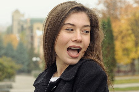 Portrait of a beautiful girl who has fun walking along the street. She expresses her emotions...