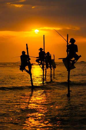 Silhouettes of the traditional stilt fishermen at sunsetの写真素材
