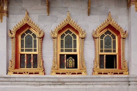 Three windows of the thai temple placed repeatedly. They are decorated with low relief and colored...