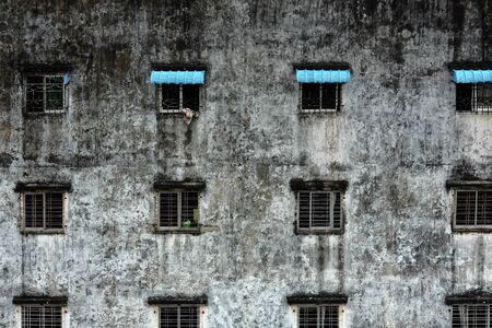Wrecked windows are repeatedly located on the old wall of the low rise building.の写真素材