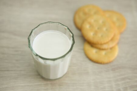 A glass of milk with pile of crackers on the wood top table.の写真素材