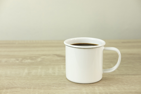 Side view of white enamel coffee cup on a wood table.の写真素材