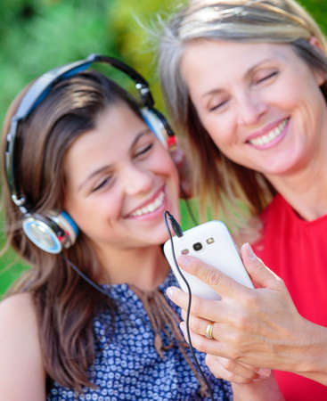 beautful young girl with her mother listening music together with complicityの写真素材