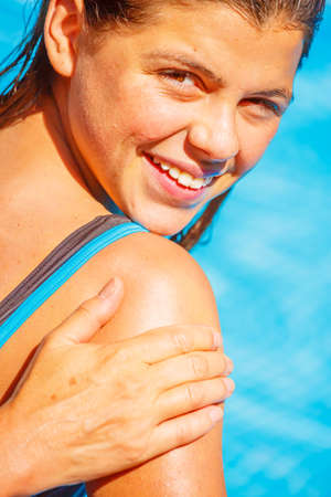 A mum applying a protect sun cream on the shoulders  of her smiling young girl