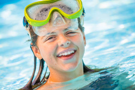 Beautiful portrait of young smiling girl in the water with diving mask on her headの写真素材
