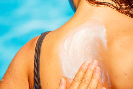 A mum applying a protect sun cream on the back of her young girl