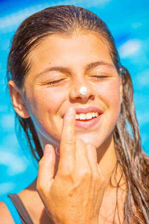 A mum applying a protect sun cream on the face of her smiling young girlの写真素材