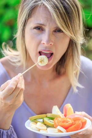 attractive blond woman eating fresh fruits