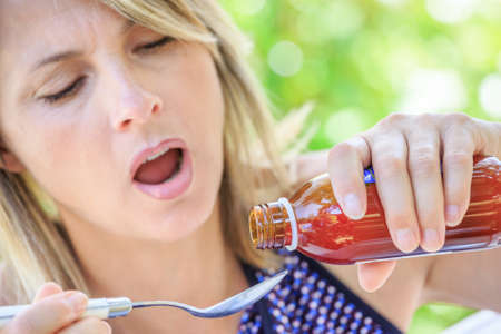 closeup of attractive woman taking a syrup on a spoonの写真素材