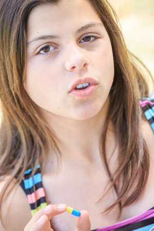 young girl taking medicine in pill with water glassの写真素材