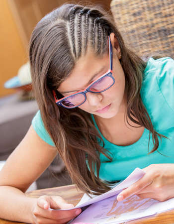 closeup of a pretty student girl doing homework at homeの写真素材