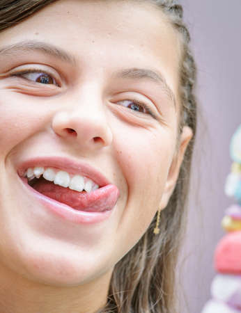 closeup of pretty young girl eating a delicious marshmallow skewer